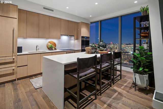 kitchen with a wall of windows, a center island, dark hardwood / wood-style floors, and sink