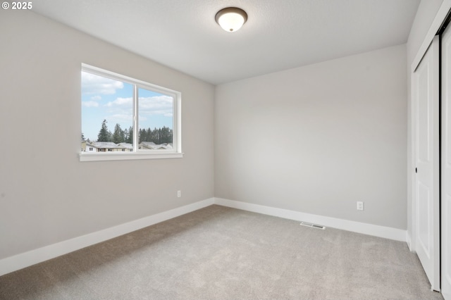 unfurnished bedroom with light colored carpet and a closet