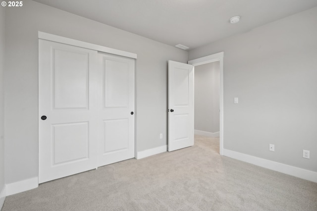 unfurnished bedroom featuring light colored carpet and a closet