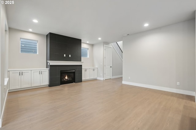 kitchen featuring light wood-type flooring, an island with sink, decorative light fixtures, dark brown cabinets, and stainless steel appliances