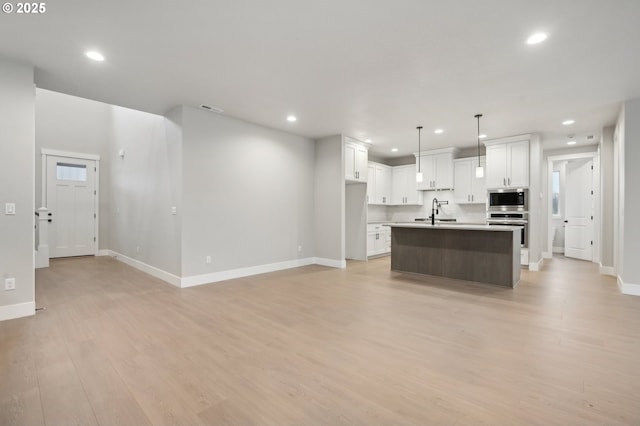 kitchen with pendant lighting, sink, a breakfast bar area, an island with sink, and stainless steel appliances