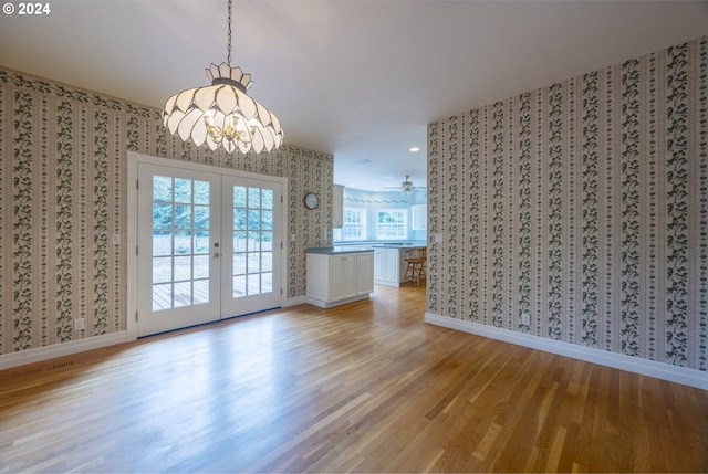 interior space featuring ceiling fan with notable chandelier, light wood-type flooring, and french doors