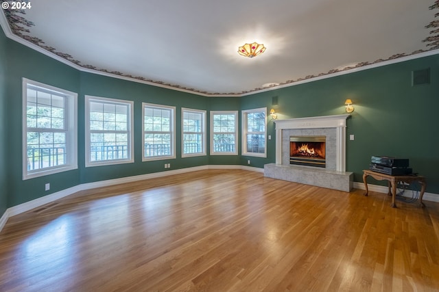 unfurnished living room with light wood-type flooring, crown molding, and a tiled fireplace