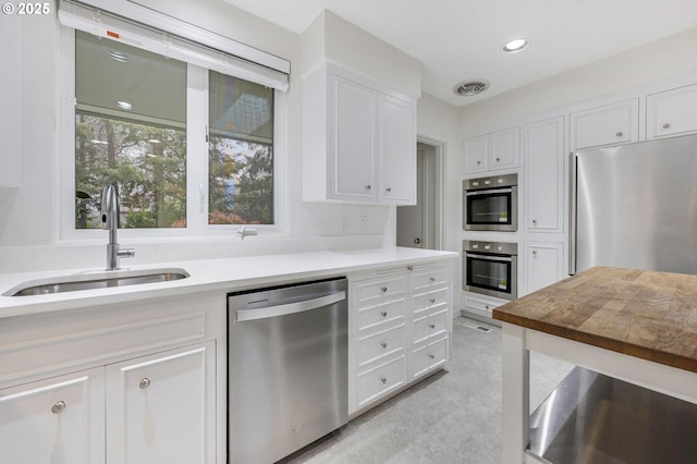 kitchen featuring appliances with stainless steel finishes, white cabinets, and sink