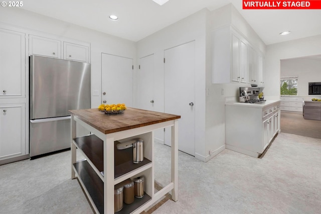 kitchen with white cabinetry, butcher block counters, and stainless steel fridge