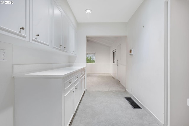 hallway with light colored carpet and lofted ceiling