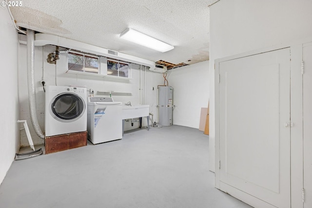 washroom with water heater, a textured ceiling, washing machine and clothes dryer, and sink