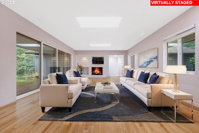 living room with light wood-type flooring and a skylight