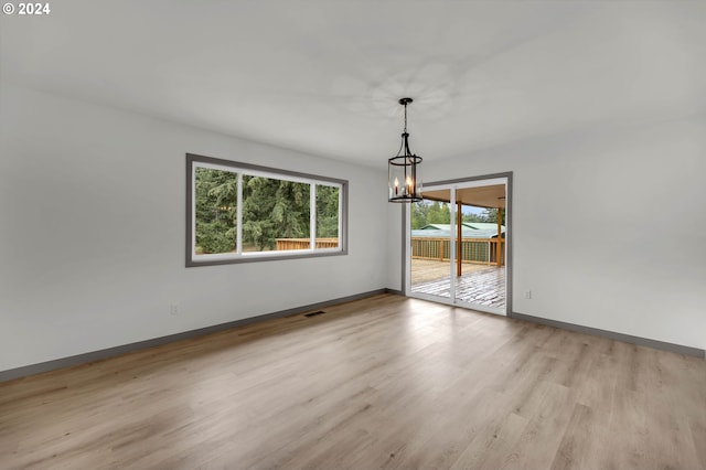 unfurnished room featuring light wood-type flooring and a notable chandelier