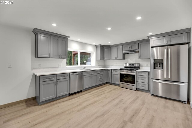 kitchen featuring stainless steel appliances, sink, gray cabinets, and light wood-type flooring