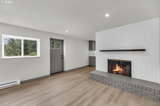 unfurnished living room with a fireplace, a baseboard radiator, and light hardwood / wood-style floors