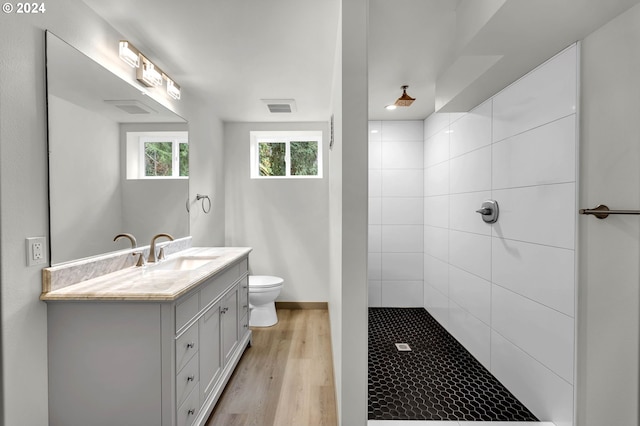 bathroom with vanity, toilet, wood-type flooring, and a tile shower