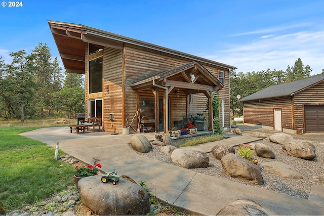 rear view of property with a patio area, an outbuilding, and a garage