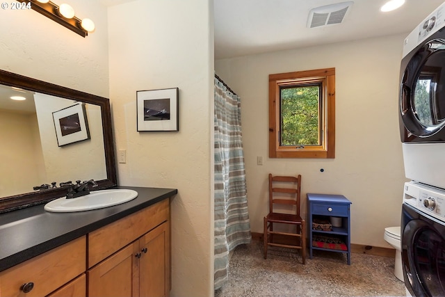 bathroom with a shower with shower curtain, vanity, stacked washing maching and dryer, and toilet