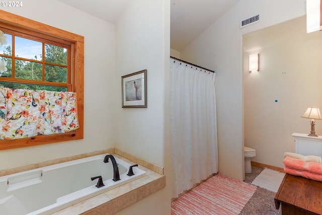 bathroom with a relaxing tiled tub, toilet, and vaulted ceiling