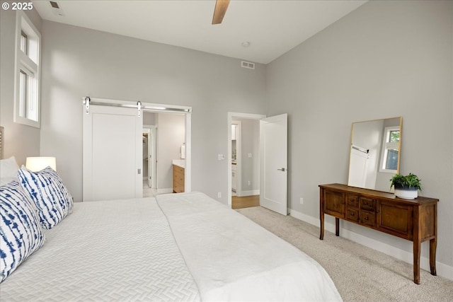 bedroom featuring visible vents, a barn door, baseboards, a high ceiling, and carpet flooring