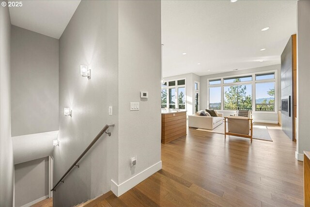 corridor featuring baseboards, a wealth of natural light, wood finished floors, and an upstairs landing