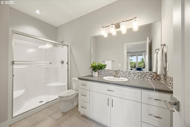 bathroom featuring an enclosed shower, vanity, decorative backsplash, and toilet