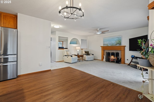 living room featuring a tile fireplace, ceiling fan with notable chandelier, and light wood-type flooring