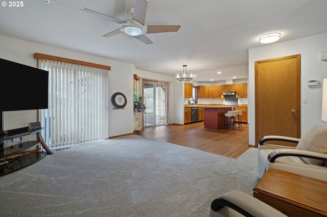 carpeted living room with ceiling fan with notable chandelier