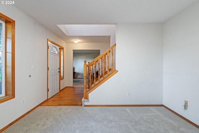 carpeted foyer entrance featuring a skylight