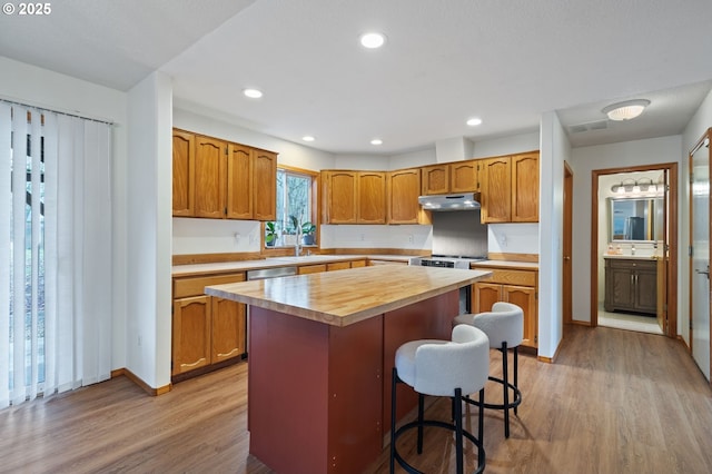 kitchen with light wood-type flooring, a breakfast bar, stainless steel appliances, sink, and a center island