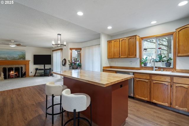 kitchen featuring a center island, sink, stainless steel dishwasher, decorative light fixtures, and a tiled fireplace