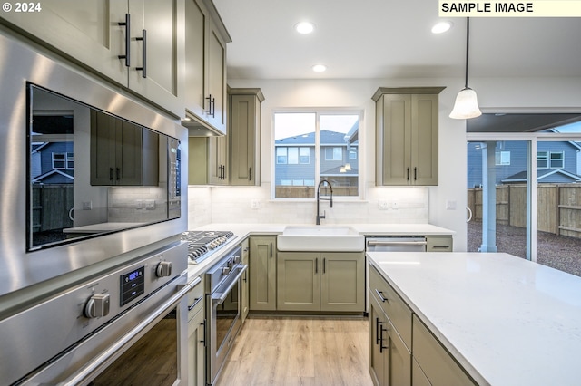 kitchen with tasteful backsplash, light hardwood / wood-style flooring, hanging light fixtures, and sink