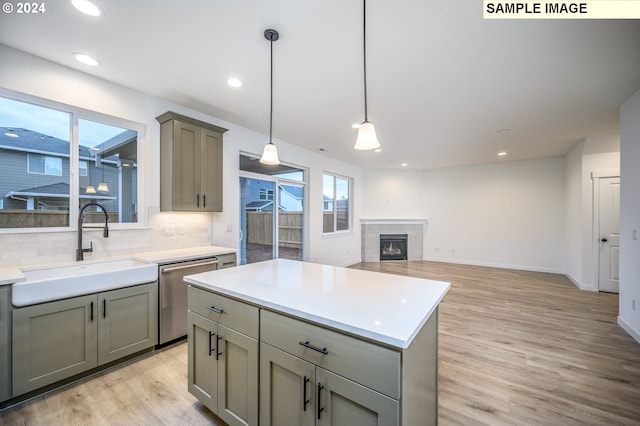 kitchen with backsplash, sink, hanging light fixtures, stainless steel dishwasher, and light wood-type flooring