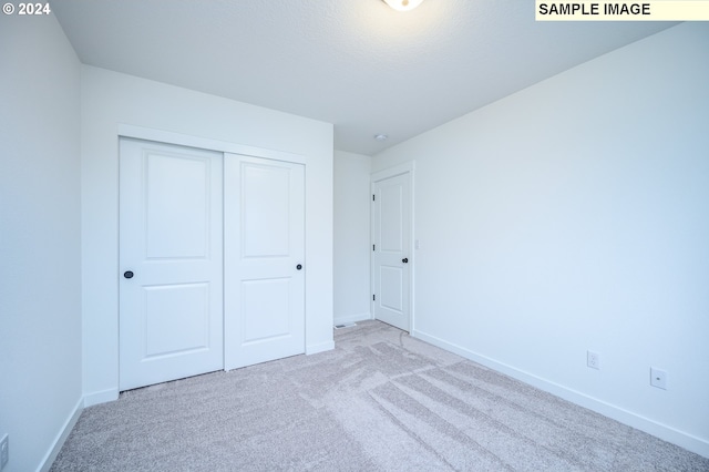 unfurnished bedroom featuring light carpet and a closet