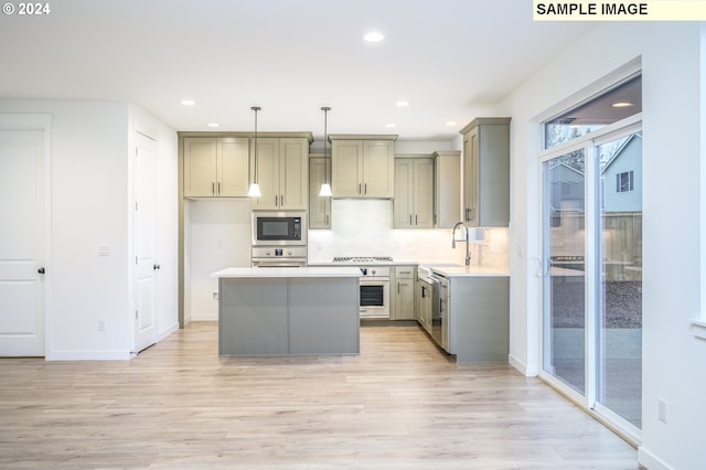 kitchen featuring light hardwood / wood-style flooring, a kitchen island, hanging light fixtures, and appliances with stainless steel finishes