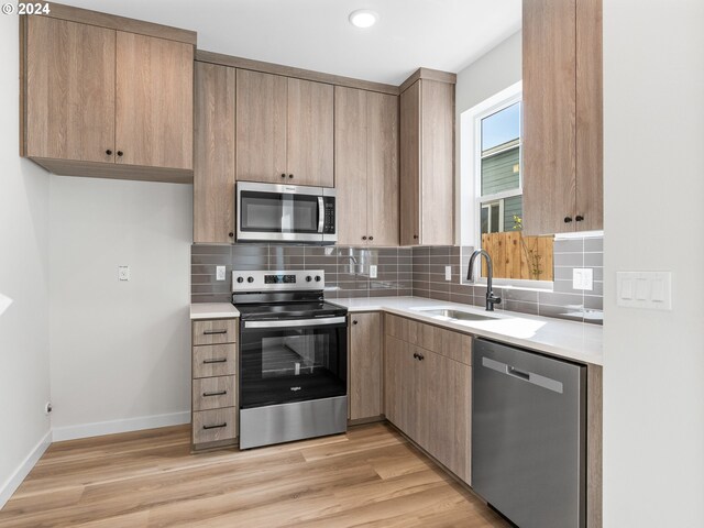 7471 N New York Ave Unit 3, Portland, OR 97203 - kitchen with decorative backsplash, light countertops, light wood finished floors, stainless steel appliances, and a sink