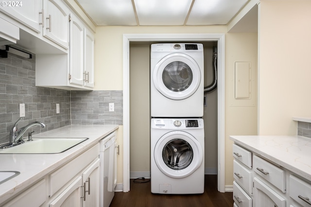 laundry area featuring sink, electric panel, stacked washing maching and dryer, and dark wood-type flooring