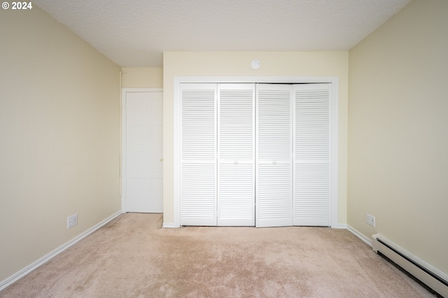 unfurnished bedroom featuring light carpet, a textured ceiling, a baseboard radiator, and a closet