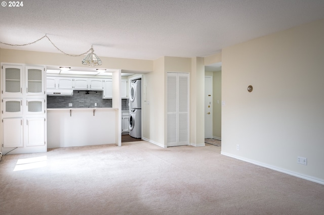 interior space with a textured ceiling, stacked washing maching and dryer, and light carpet