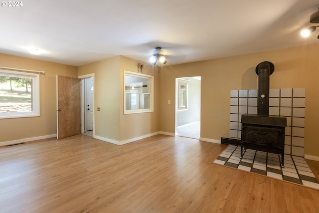 living room with light hardwood / wood-style flooring, a wood stove, and ceiling fan