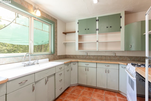 kitchen featuring white cabinetry, gas range gas stove, light tile patterned floors, and sink