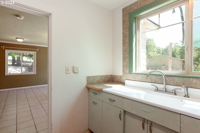 bathroom with tile patterned flooring, vanity, a healthy amount of sunlight, and ornamental molding