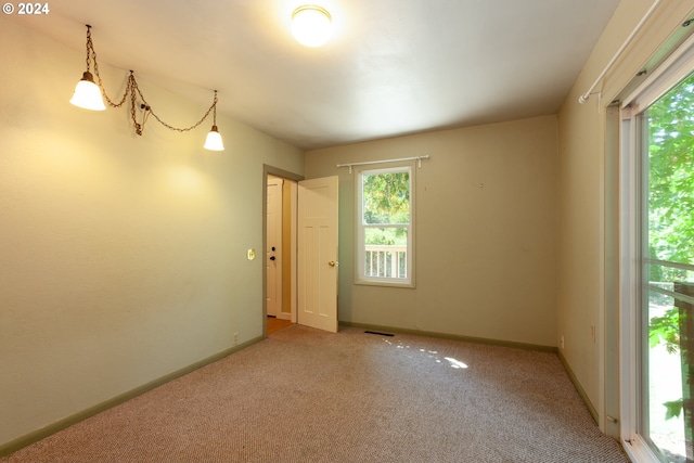 carpeted empty room with a chandelier