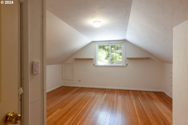 additional living space with light hardwood / wood-style floors and vaulted ceiling