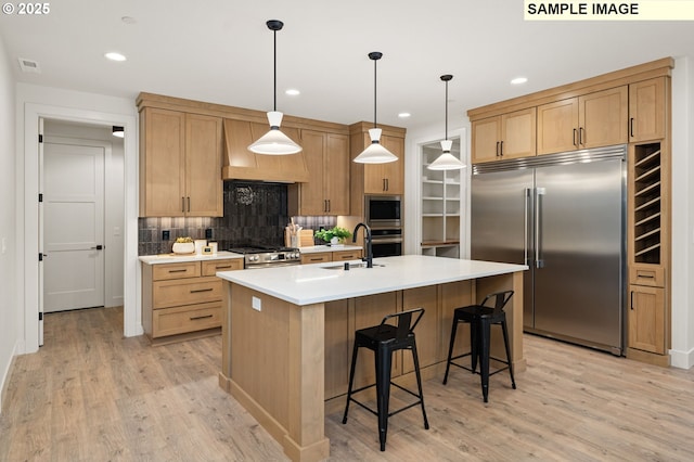 kitchen featuring built in appliances, custom exhaust hood, light countertops, pendant lighting, and a sink