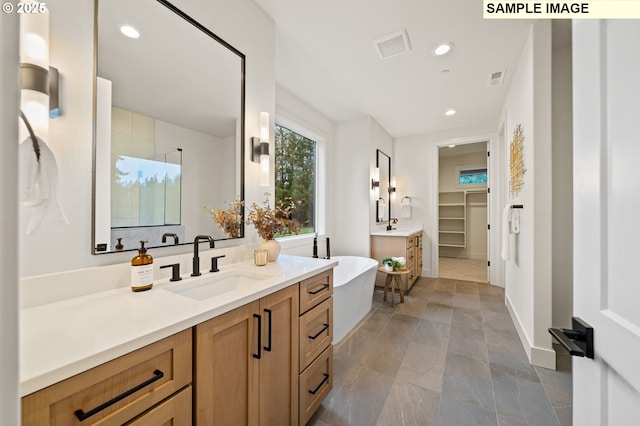 bathroom featuring visible vents, a sink, a walk in closet, two vanities, and recessed lighting