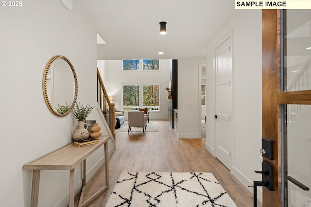 entryway with light wood-style floors, stairway, and baseboards