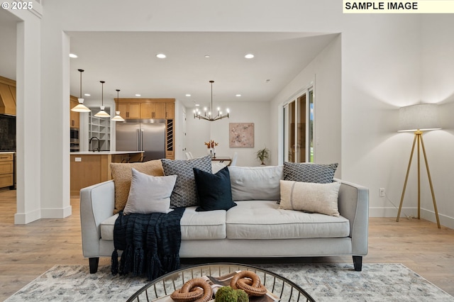 living area featuring recessed lighting, a notable chandelier, light wood-style flooring, and baseboards