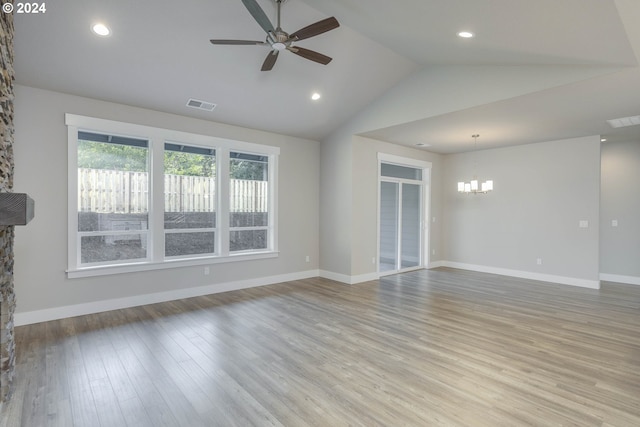 unfurnished living room featuring ceiling fan with notable chandelier, a fireplace, light hardwood / wood-style flooring, and vaulted ceiling