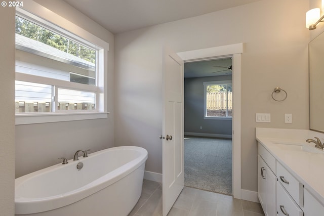 bathroom with tile patterned flooring, plenty of natural light, a bath, and vanity