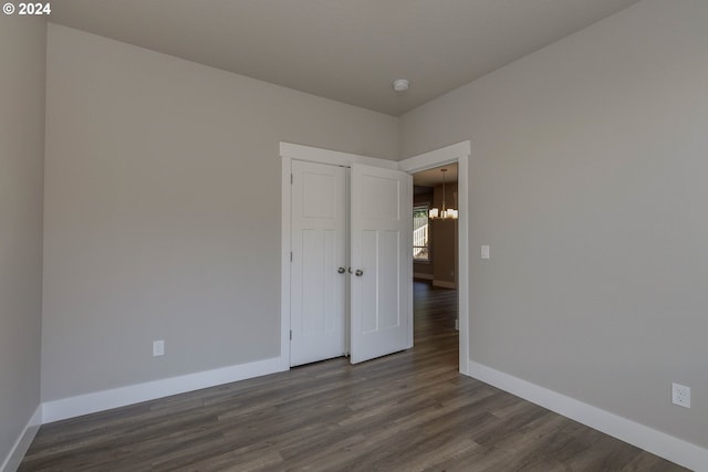 spare room featuring dark hardwood / wood-style floors and a notable chandelier