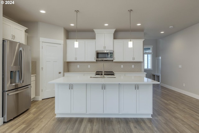 kitchen with pendant lighting, stainless steel appliances, and a center island with sink