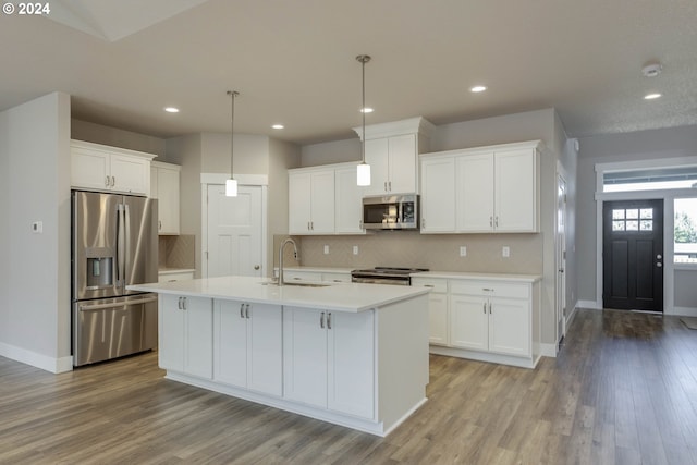 kitchen featuring appliances with stainless steel finishes, sink, light hardwood / wood-style flooring, white cabinetry, and hanging light fixtures