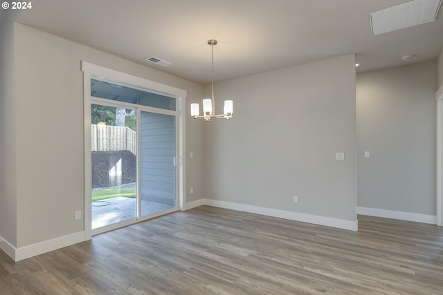 spare room with a notable chandelier and light wood-type flooring